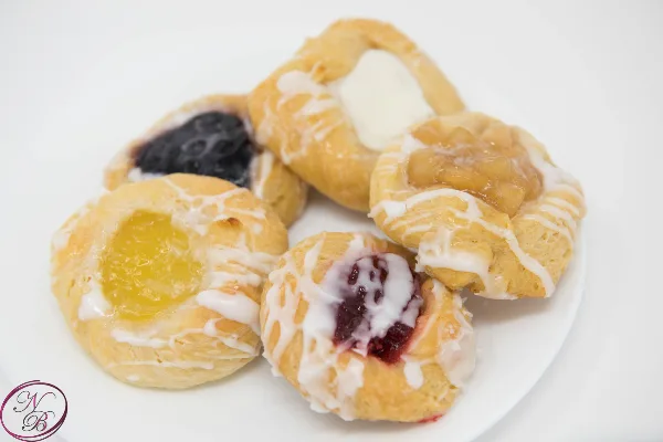 A plate of assorted fruit danishes with white icing drizzle
