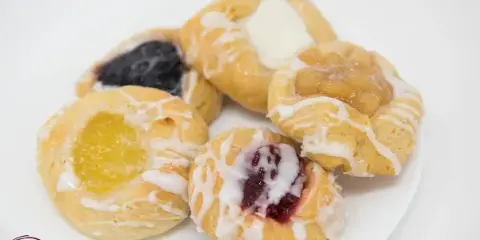 A plate of assorted fruit danishes with white icing drizzle