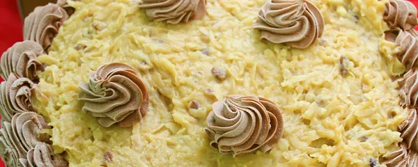 A decorated cake topped with yellow frosting and chocolate rosettes