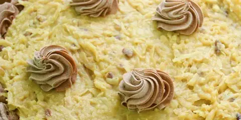 A decorated cake topped with yellow frosting and chocolate rosettes