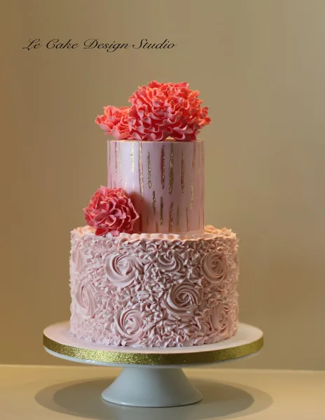 Two-tier pink and lavender cake decorated with piped flowers