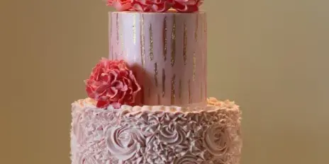 Two-tier pink and lavender cake decorated with piped flowers