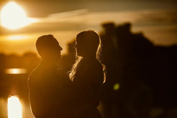 A romantic silhouette of a couple facing each other against a golden sunset.