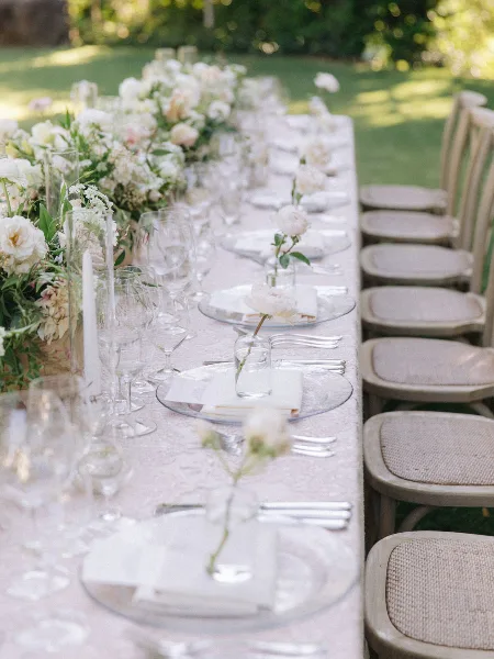 Outdoor wedding reception table with floral arrangements, glassware, and place settings