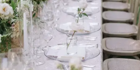 Outdoor wedding reception table with floral arrangements, glassware, and place settings