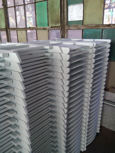 A tall stack of white folding chairs stored in a warehouse setting.