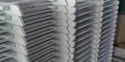 A tall stack of white folding chairs stored in a warehouse setting.