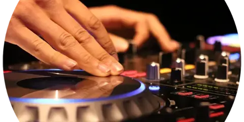 Close-up of a DJ's hands adjusting controls on a professional turntable and mixer with illuminated buttons.