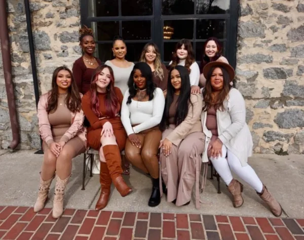 A group of ten women, presumably the beauty team, posing together in front of a stone building.