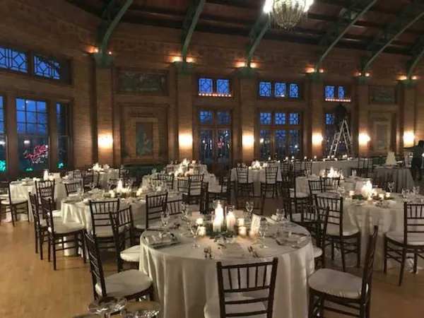 Elegant brick ballroom reception with crystal chandeliers and round tables