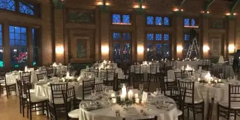 Elegant brick ballroom reception with crystal chandeliers and round tables