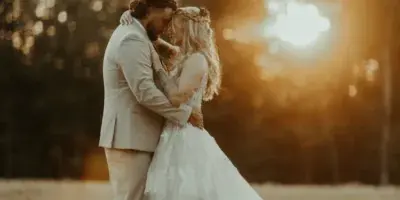 A bride and groom embracing in a field during a sunset wedding photoshoot.