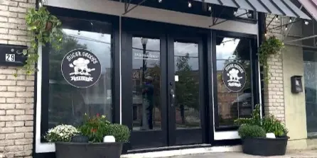 Exterior view of Sugar Daddy's Bakery storefront with black awning, glass doors, and business logo on windows.