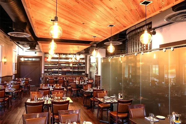 Interior view of the Cuvee 30A dining room with wooden ceilings, pendant lighting, and set tables.