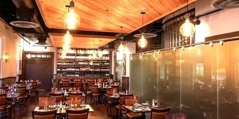 Interior view of the Cuvee 30A dining room with wooden ceilings, pendant lighting, and set tables.