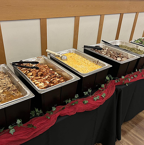 Buffet-style catering with BBQ meats, mac-n-cheese, potatoes, and fresh green beans.