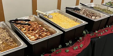 Buffet-style catering with BBQ meats, mac-n-cheese, potatoes, and fresh green beans.