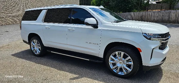A white Chevrolet Suburban SUV parked on a paved surface.