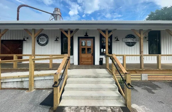 Exterior view of a white building with wooden porch railings and signage for The Street Kitchen at Berlin Beer Co.