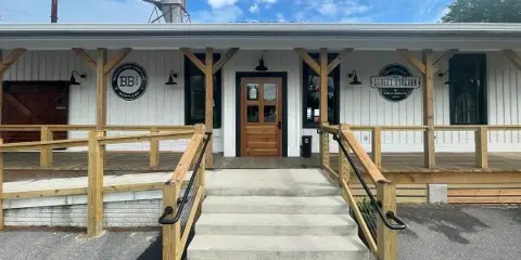 Exterior view of a white building with wooden porch railings and signage for The Street Kitchen at Berlin Beer Co.
