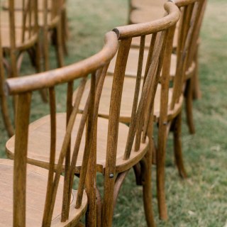 Rows of wooden dining chairs arranged on grass for an outdoor event