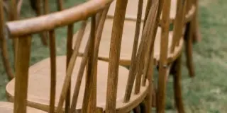 Rows of wooden dining chairs arranged on grass for an outdoor event