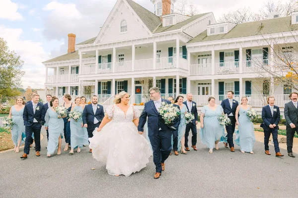 A wedding party walking in front of the white Manor House at Kent Island Resort.