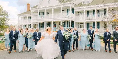 A wedding party walking in front of the white Manor House at Kent Island Resort.