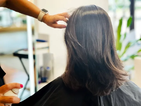 A stylist styling a client's hair in a salon.