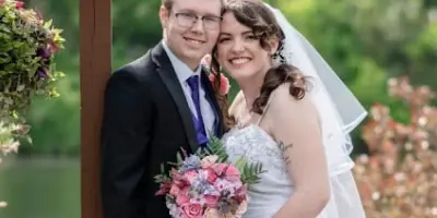 A bride and groom posing together outdoors with a bouquet, representing a wedding at the venue.