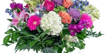 A colorful floral arrangement featuring lilies, roses, and chrysanthemums in a clear glass vase.