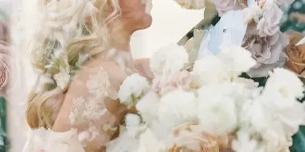 A bride and groom sharing a moment, with the bride holding a large, romantic bouquet of white and blush roses.