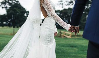 A bride and groom holding hands outdoors during a wedding ceremony.