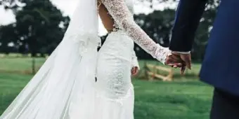 A bride and groom holding hands outdoors during a wedding ceremony.