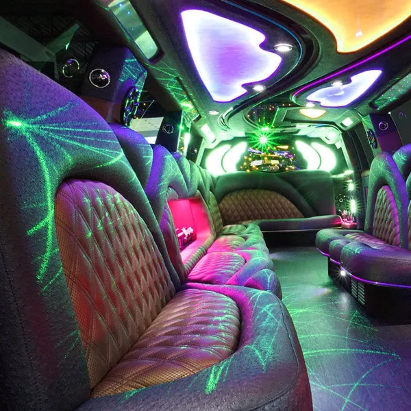 Interior of a party bus featuring plush wraparound seating and vibrant green and purple lighting.
