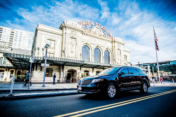 A black luxury SUV parked on a city street in front of the Union Station building.