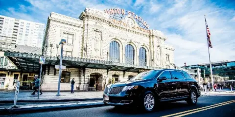 A black luxury SUV parked on a city street in front of the Union Station building.