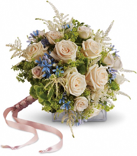 A round bouquet of cream roses and blue flowers with a pink ribbon tied to the stems.