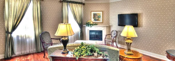 Interior of a hotel suite featuring a fireplace, patterned wallpaper, and classic furniture.