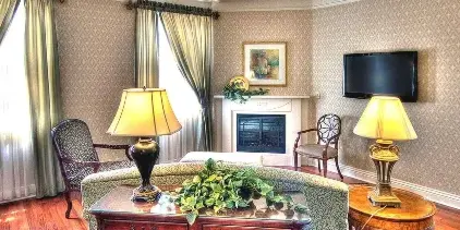 Interior of a hotel suite featuring a fireplace, patterned wallpaper, and classic furniture.