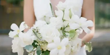 Bride in a white dress holding a bouquet of white roses and garden flowers