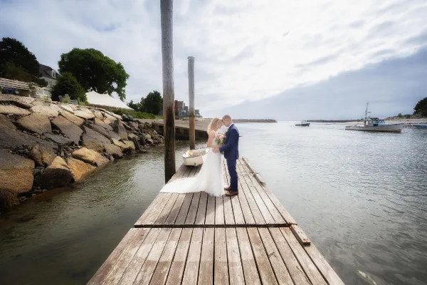 Bride and groom standing on a wooden dock by the water
