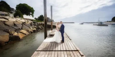 Bride and groom standing on a wooden dock by the water