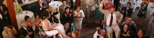 A bride and groom dancing at a wedding reception surrounded by guests.