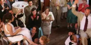 A bride and groom dancing at a wedding reception surrounded by guests.