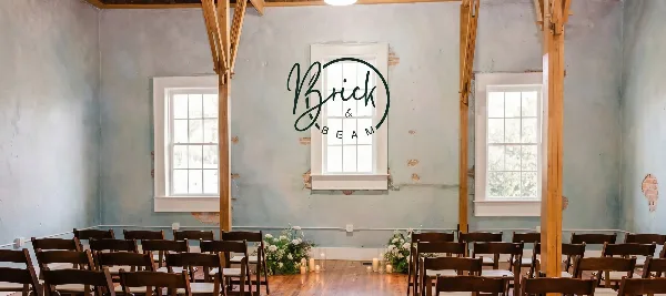 Interior of a historic event venue with exposed wooden beams, blue plaster walls, and a ceremony setup with chairs and floral arrangements.