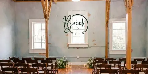 Interior of a historic event venue with exposed wooden beams, blue plaster walls, and a ceremony setup with chairs and floral arrangements.