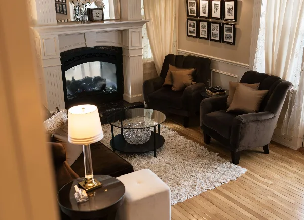 Interior view of a lounge featuring a white fireplace, dark armchairs, and a glass coffee table.