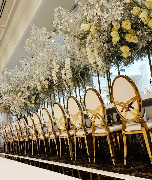 A row of gold and white luxury chairs arranged in a ballroom setting.
