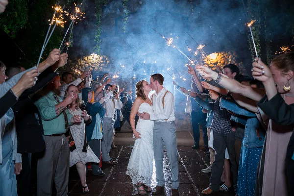 Bride and groom kissing during a sparkler send-off at a wedding reception.